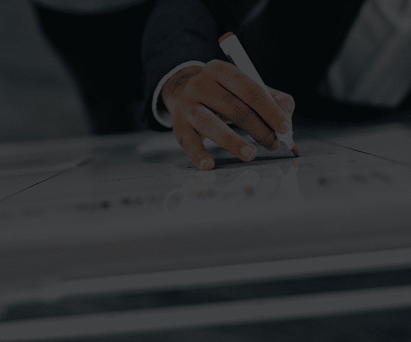 Person writing on a clear glass surface with a whiteboard marker, focusing on their hand and the marker.